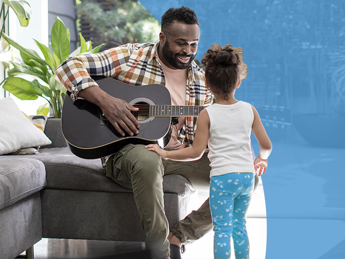 A father playing guitar with his daughter at home